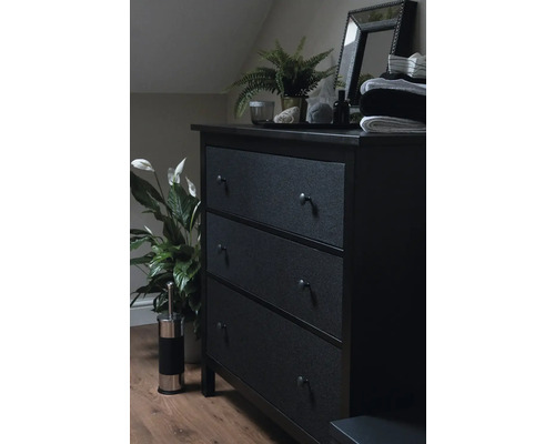 Tmavá komoda s tromi zásuvkami, zrkadlo, rastlina a dekorácia v spálni.