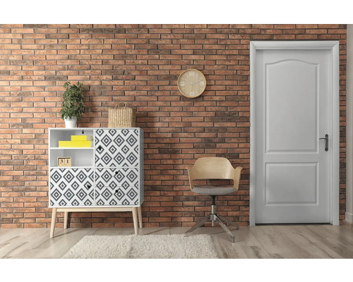 Obývacia izba s komodou, stoličkou a dverami pred tehlovou stenou.