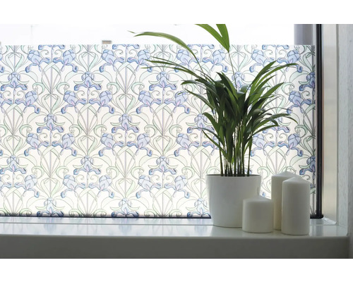 Okno so statickou okennou fóliou s kvetinovým vzorom, črepníkovou rastlinou a sviečkami