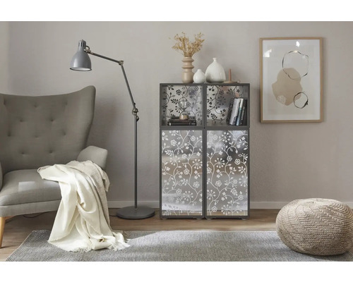 Obývacia izba so sedadlom, stojacou lampou, kobercom, stoličkou a regálom s kvetinovým vzorom