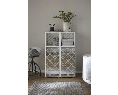 Kúpeľňová scéna s bielym policovým systémom s dvoma hornými priehradkami a dvoma spodnými dvierkami skriniek, zdobená kúpeľňovými potrebami a textilom