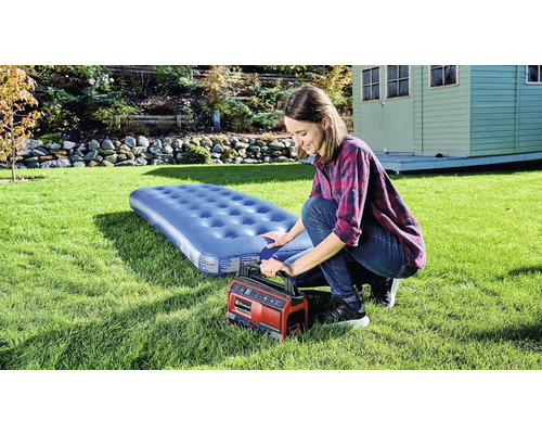 Žena nafukuje matrac elektrickou pumpou na záhrade.