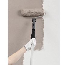 Maliar s valčekom a teleskopickou tyčou maľuje stenu