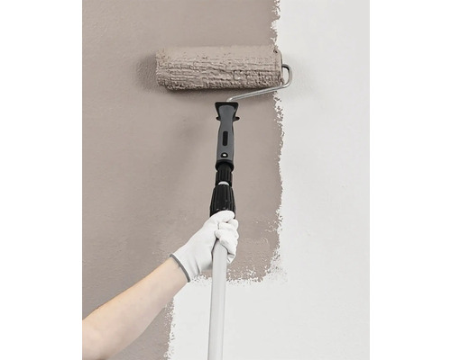 Maliar s valčekom a teleskopickou tyčou maľuje stenu