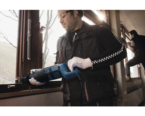 Remeselník demontuje okno pomocou chvostovej píly.