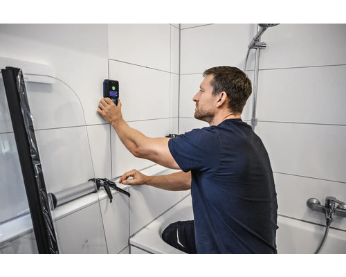 Muž používa skener stien v kúpeľni na rekonštrukciu kúpeľne.