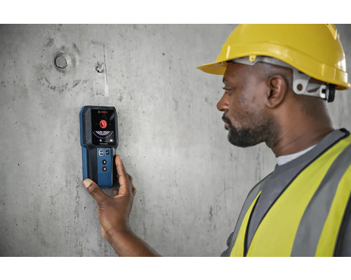 Stavebný robotník používa detektor Bosch na betónovej stene