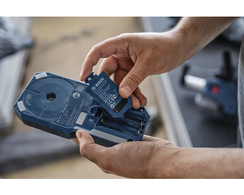 Muž vkladá batériu do vyhľadávača Bosch