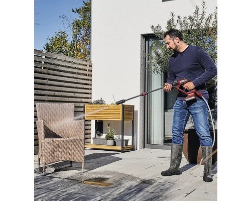 Muž čistí terasu vonku pomocou tlakovej umývačky.