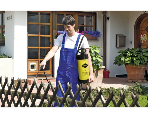 Muž používa záhradný postrekovač Mesto na záhradníctvo pred domom.