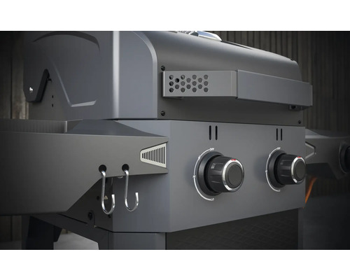 Detail plynového grilu s otočnými ovládačmi a háčikmi