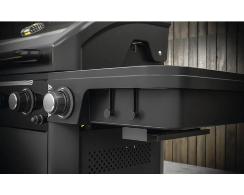 Detail plynového grilu s bočným stolíkom, otočnými gombíkmi a lištou s háčikmi