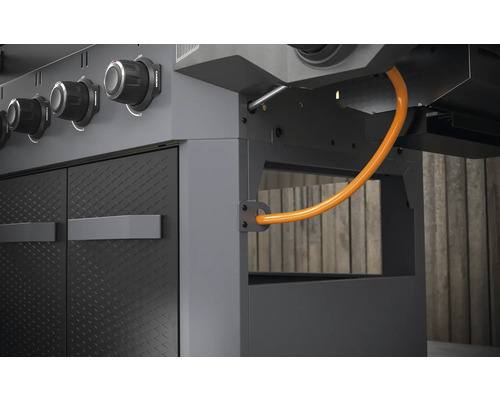 Detailný pohľad na plynový gril s ovládacími gombíkmi, dvierkami a plynovou hadicou