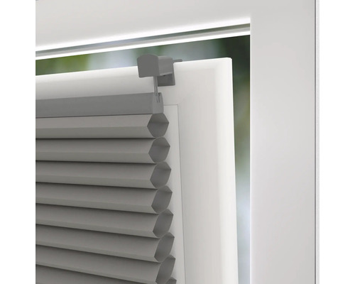 Detailný pohľad na sivú plisovanú žalúziu na okne