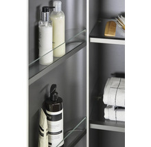 Detail kúpeľňovej skrinky s ošetrujúcimi produktmi, uterákmi a kefami na sklenených policiach