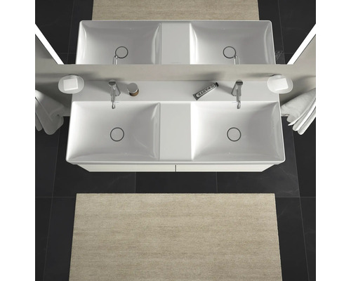 Pohľad zhora na dvojité umývadlo s batériami, miskami na mydlo, uterákmi a koberec v kúpeľni.