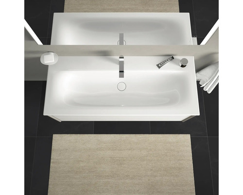 Pohľad zhora na kúpeľňu s umývadlom, zrkadlom, batériou, dávkovačom mydla, zubnou pastou, uterákom a kúpeľňovou predložkou