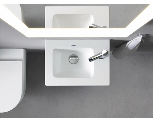 Pohľad zhora na kúpeľňu s umývadlom, zrkadlom s osvetlením, uterákom a toaletou.