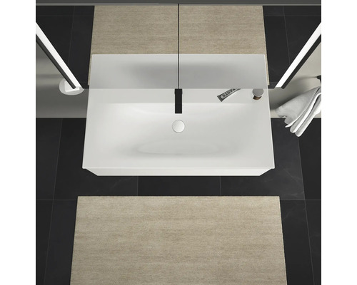 Pohľad zhora na kúpeľňu s umývadlom, batériou, uterákom a kúpeľňovými predložkami