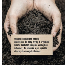 Ruky držia hrsť zeminy s informačnou ceduľkou o hnojive.