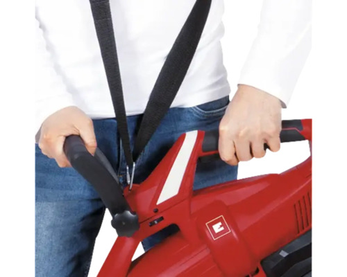 Osoba drží v ruke červený vysávač lístia s popruhom.