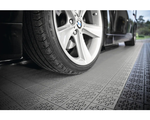 Auto stojí na garážových dlaždiciach s drenážnym vzorom.