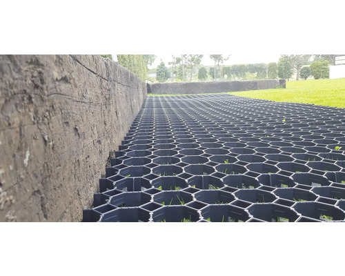 Detailný záber cesty spevnenej zatrávňovacími dlaždicami vedľa steny