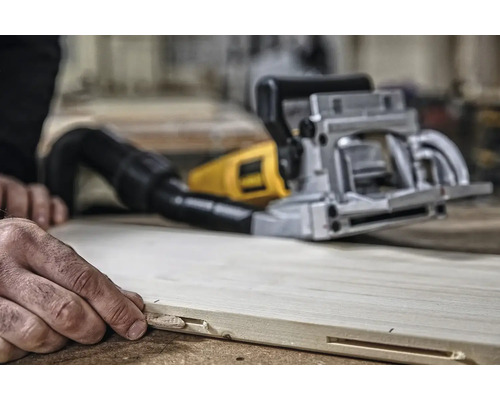 Osoba používa drážkovaciu frézu na drevenej doske na vytvorenie drážky.