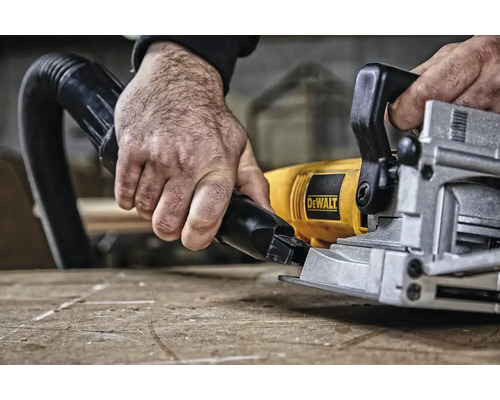 Ruka drží hadicu vysávača na kotúčovej píle Dewalt.