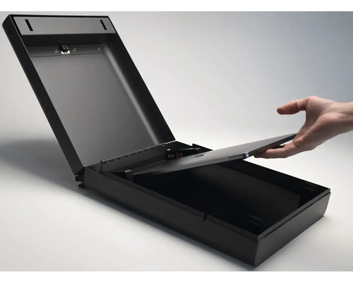 Otvorený, čierny nástenný trezor s rukou vkladajúcou dovnútra ploché elektronické zariadenie