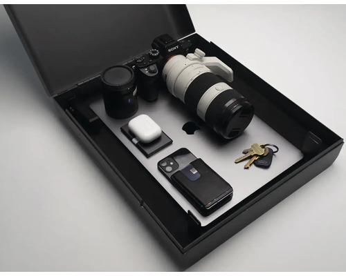 Elektronické zariadenia, ako je fotoaparát, notebook a slúchadlá v čiernej úložnej krabici.