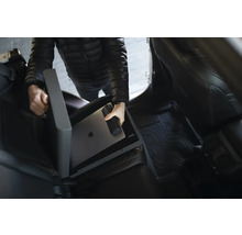 Osoba ukladá notebook a fľašu na pitie do úložného boxu do auta