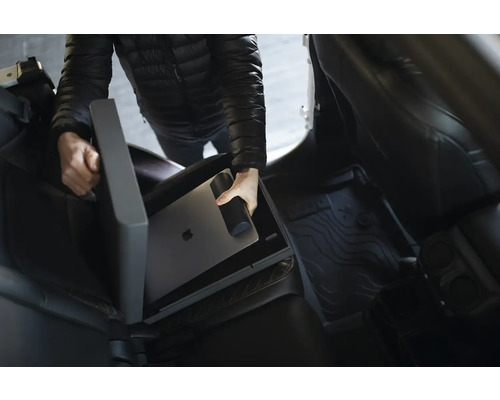 Osoba ukladá notebook a fľašu na pitie do úložného boxu do auta