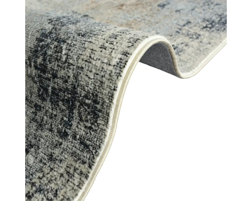 Detailný pohľad na koberec s abstraktným vzorom a obšité okraje.