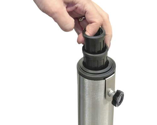 Ruka nasadzuje čiernu redukčnú objímku na kovový stojan pre slnečník.