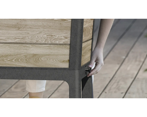 Detailný pohľad na vyvýšený záhon z dreva a kovu s osobou ovládajúcou gombík