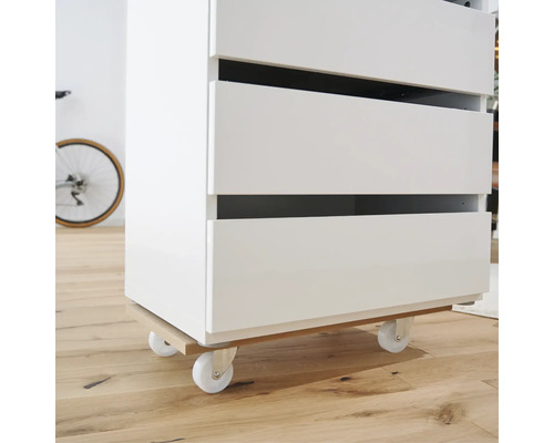 Biely zásuvkový prvok s kolieskami na drevenej podlahe