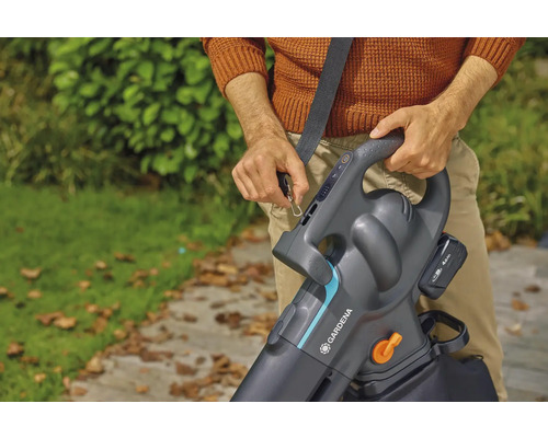 Osoba pripevňuje akumulátorový vysávač lístia Gardena s ramenným popruhom