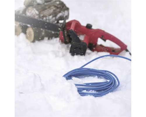 Elektrická reťazová píla a modrý predlžovací kábel v snehu