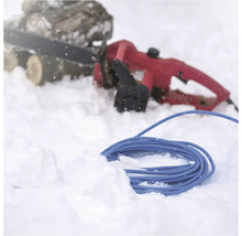Elektrická reťazová píla s predlžovacím káblom v snehu