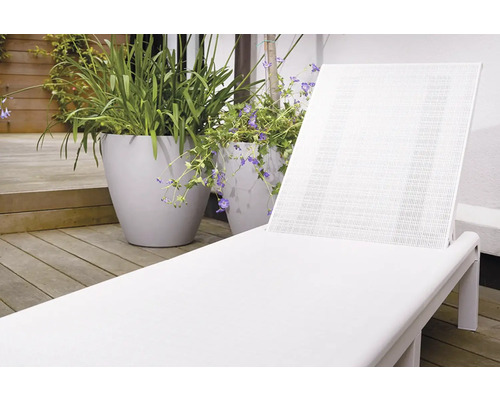 Biele plastové záhradné ležadlo vedľa kvetináčov na drevenej terase