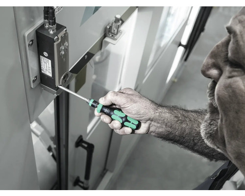 Muž používa skrutkovač na utiahnutie skrutky na elektronickom komponente.