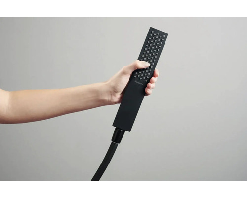 Ruka drží obdĺžnikovú ručnú sprchu s hadicou.