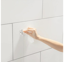 Fotografia ruky pripevňujúcej Grohe QuickFix na kúpeľňovú stenu