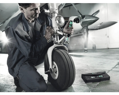 Mechanik opravuje podvozok lietadla pomocou skrutkovačov a brašny na náradie.