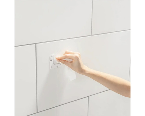 Osoba upevňuje pomocou handričky Grohe QuickFix na obloženú stenu