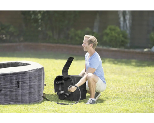 Muž pripája nafukovací vírivku na záhrade.