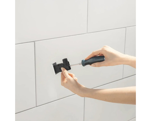 Osoba montuje upevňovaciu krabicu na obloženú stenu pomocou skrutkovača.