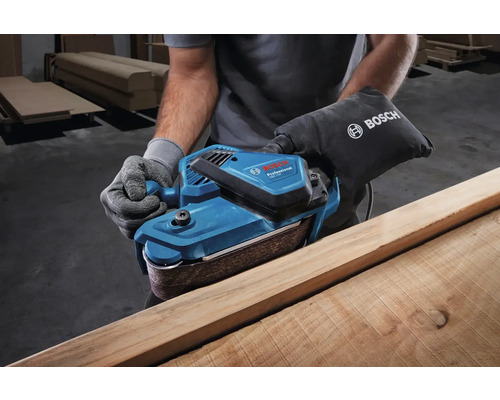 Osoba brúsi drevo pásovou brúskou Bosch