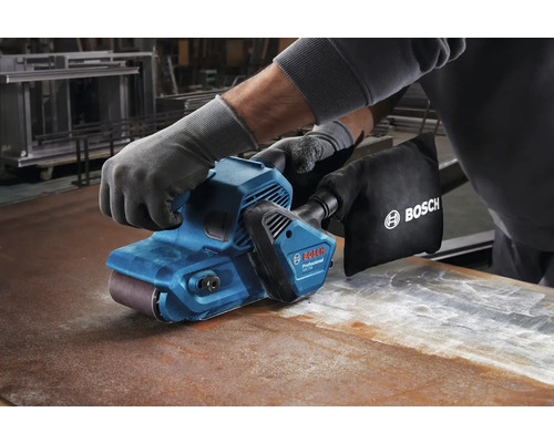 Operátor v rukaviciach používa pásovú brúsku na kovovom povrchu, Logo Bosch